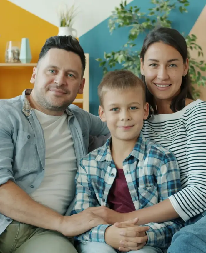 Padres adoptivos y su hijo sentados muy juntos en casa