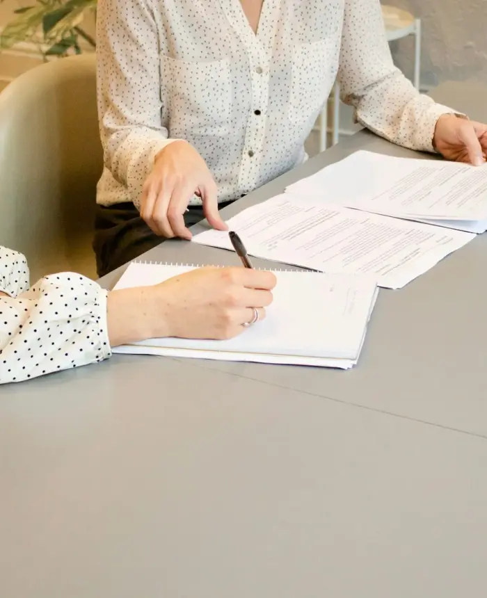 Two women reviewing and signing adoption paperwork together at a desk