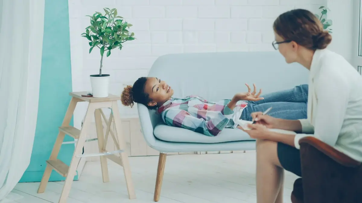 Una niña y una terapeuta conversando durante una sesión de consejería